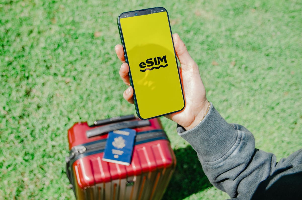 Voyageur tenant un smartphone avec l'application eSIM près des bagages — prêt à rester connecté au Mexique