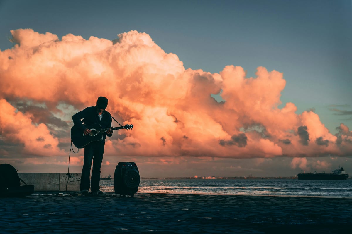 Silhouette of a guitarist playing live music by the Pacific Ocean at sunset in Puerto Escondido Mexico