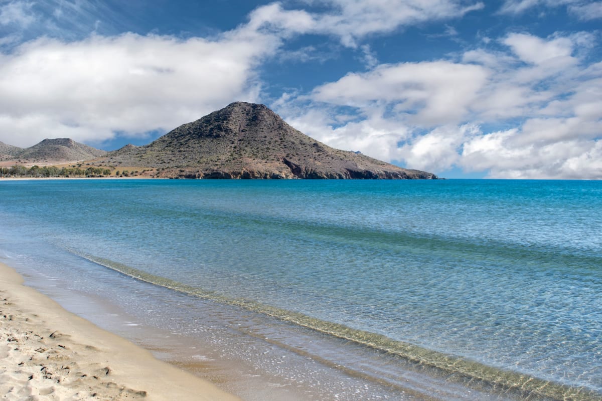 Scenic beach with sandy shore, turquoise sea, and lush mountain backdrop typical of Puerto Escondido, Mexico in February