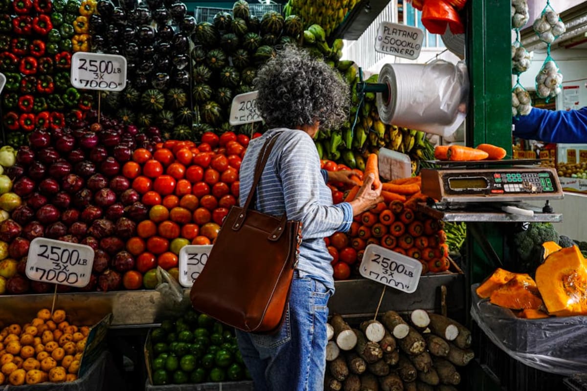 Woman shopping at a colourful local produce market in Mexico — fresh fruit and vegetables are inexpensive at Puerto Escondido's local markets, helping expats keep grocery costs low