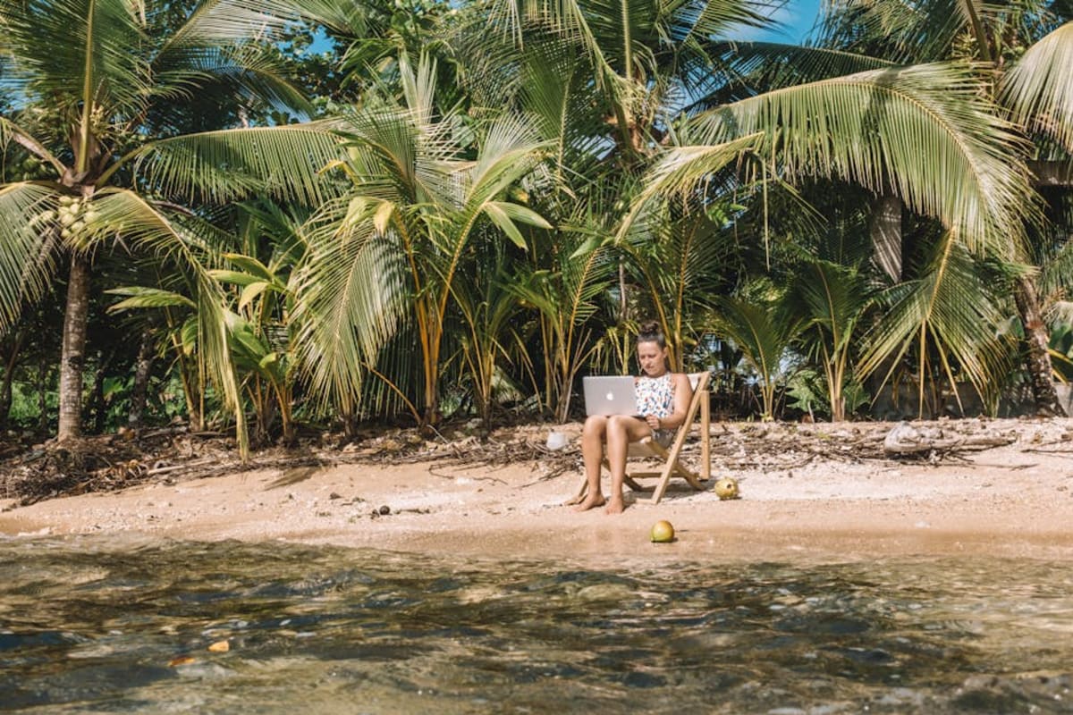 Digital nomad working on a laptop in a tropical outdoor café — high-speed internet in Puerto Escondido has improved significantly, making it viable for remote workers in 2026