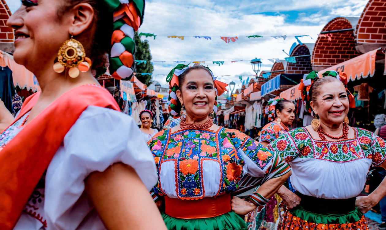 Women in vibrant traditional Mexican costumes dancing during a September cultural celebration near Puerto Escondido, Oaxaca