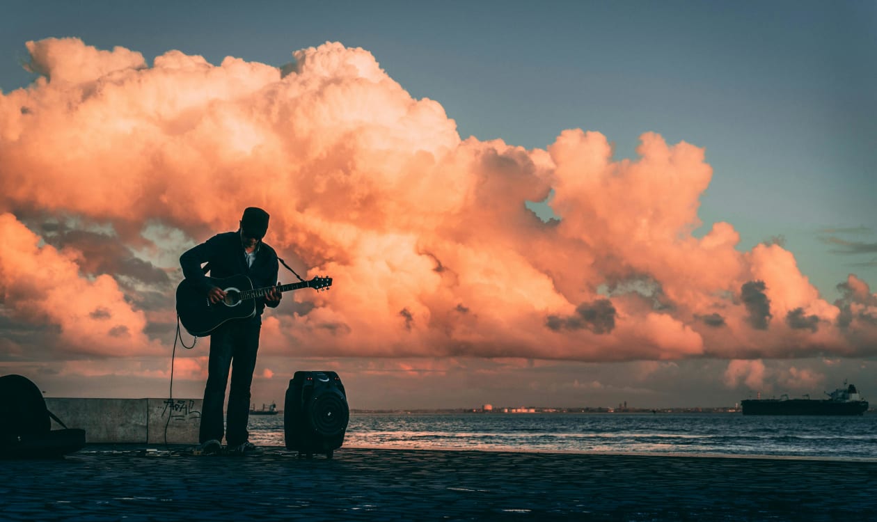 Silhouette of a guitarist playing live music by the Pacific Ocean at sunset in Puerto Escondido Mexico