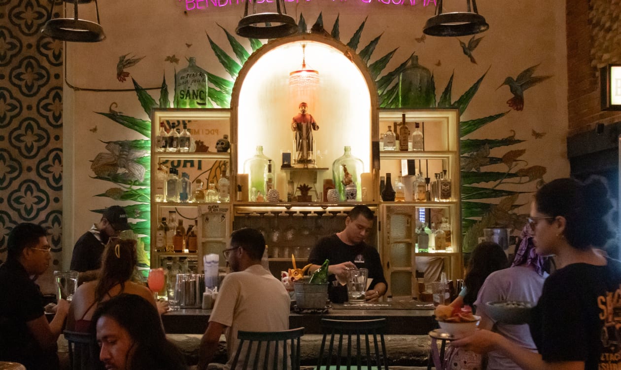Lively Mexican bar scene with locals and travelers enjoying drinks and live music in a tropical setting