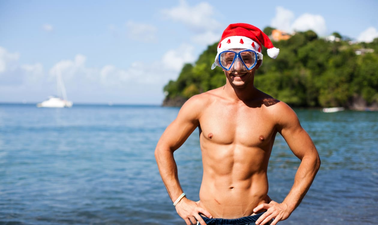 Swimmer celebrating a tropical Christmas at a Mexican beach in December, wearing a Santa hat in the warm Pacific waters near Puerto Escondido