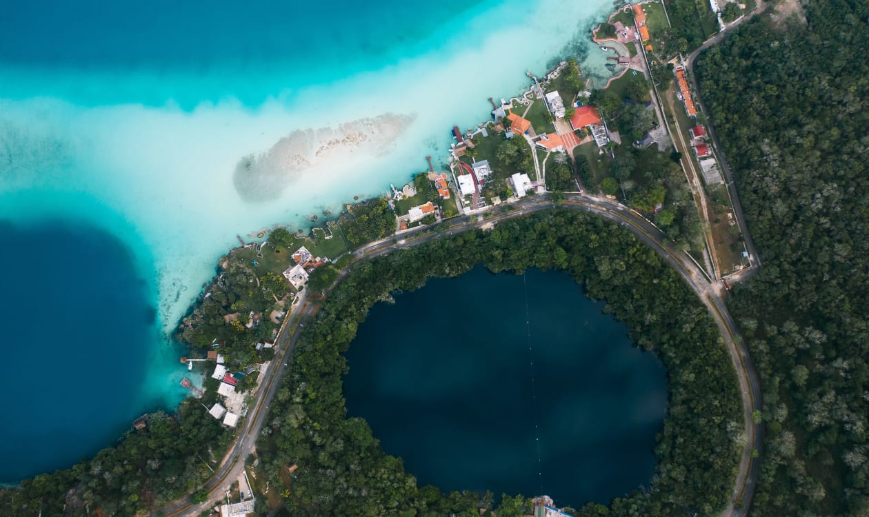 Aerial view of vibrant tropical waters meeting dense green jungle along the Mexican coast, capturing the lush scenery of Puerto Escondido in May