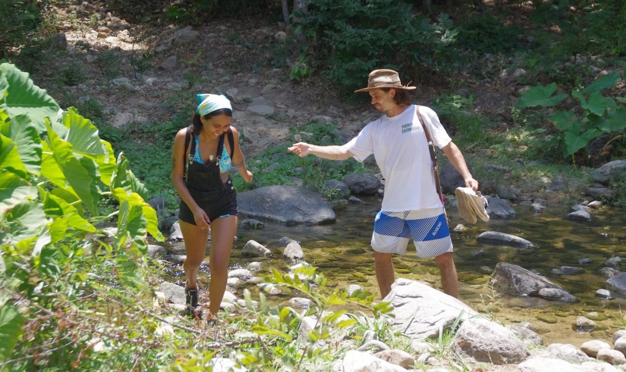 Randonneurs traversant une rivière peu profonde sur le sentier des sources chaudes d'Atotonilco près de Puerto Escondido