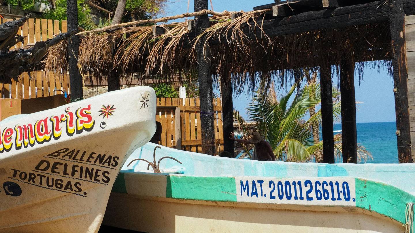 Colorful fishing boats on the shore with palapa and ocean view in Puerto Escondido