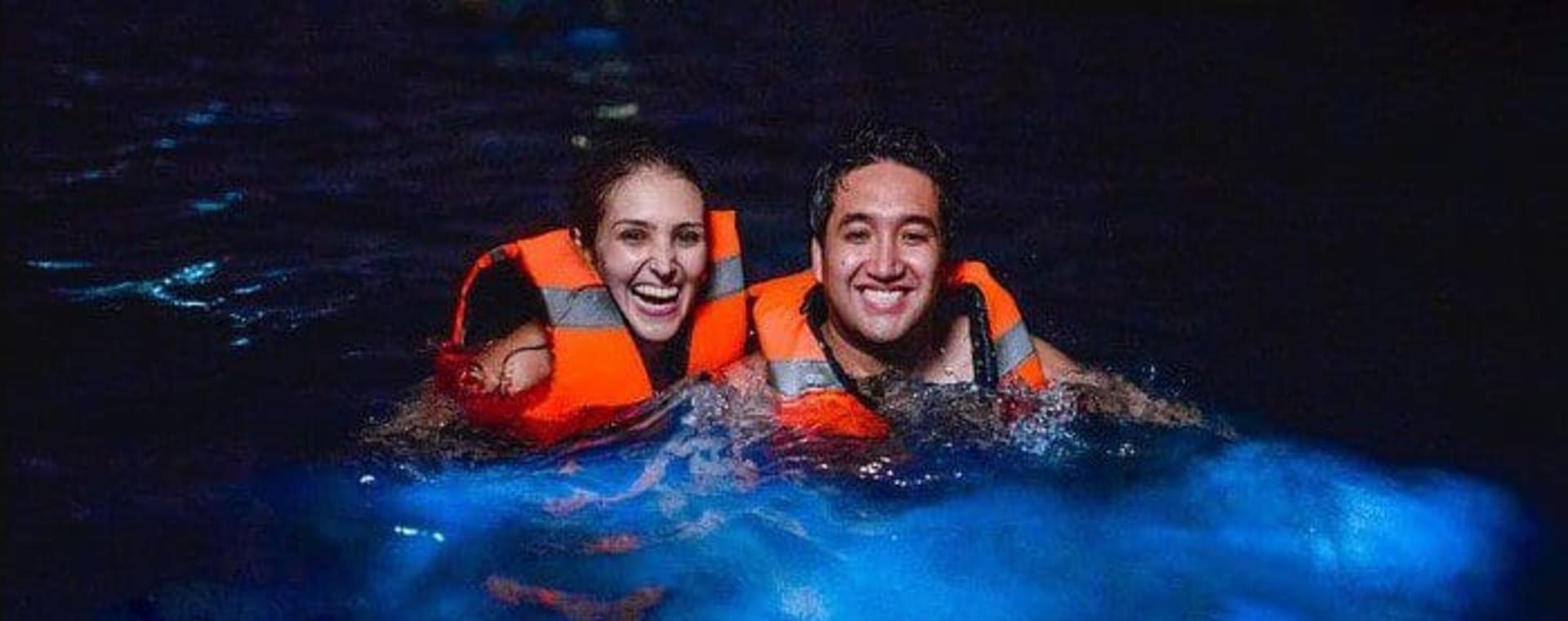 Mains soulevant de l'eau bioluminescente scintillante hors de la lagune