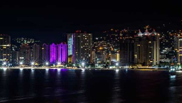 A breathtaking aerial view of Acapulco's illuminated skyline at night.