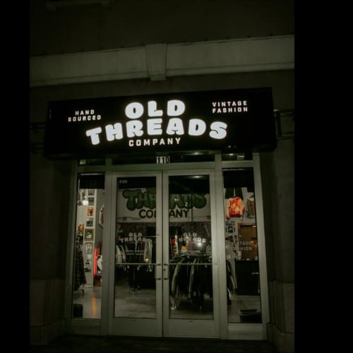 Old Threads Company storefront sign at night