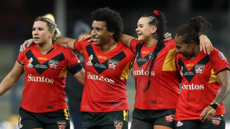 Four Papua New Guinea players link in a row, arms around each other's shoulders
