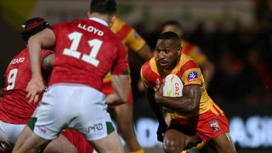 Edwin Ipape runs with the ball to attack opponents Wales