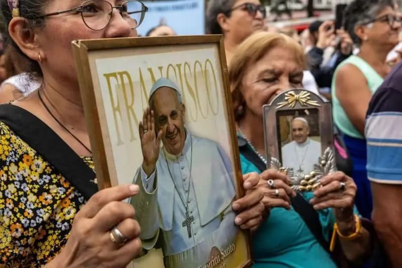 Varias mujeres sujetan retratos del Papa Francisco en una reunión de fieles católicos.