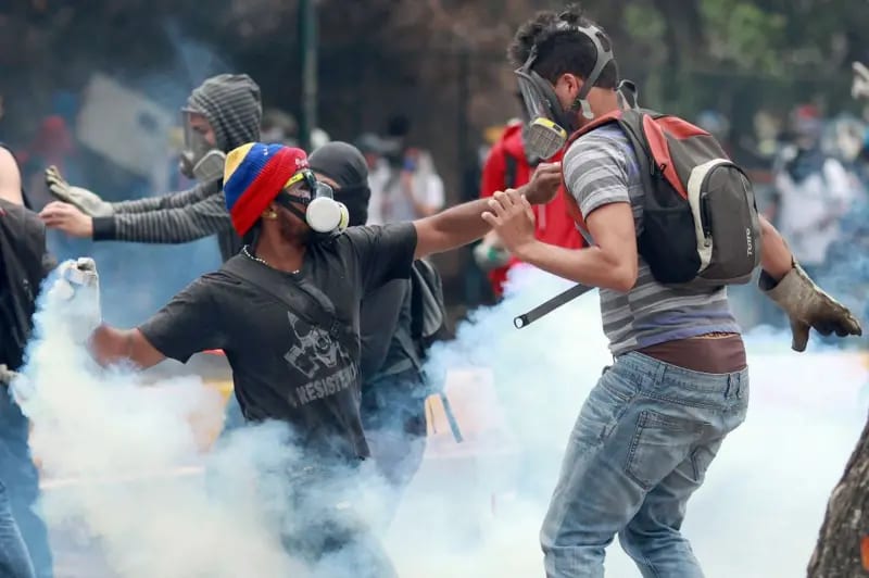 Estudiantes opositores en una protesta contra el gobierno de Nicolás Maduro en el campus de la Universidad Central de Venezuela en Caracas, el 3 de abril de 2014. Dos estudiantes con tapabocas devuelv