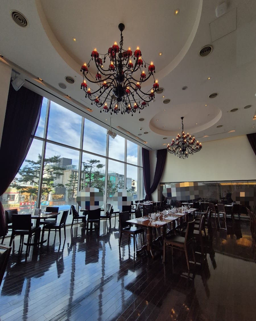 The Patio dining room at Hotel Kukdo, with a chandelier, tables and full-height windows