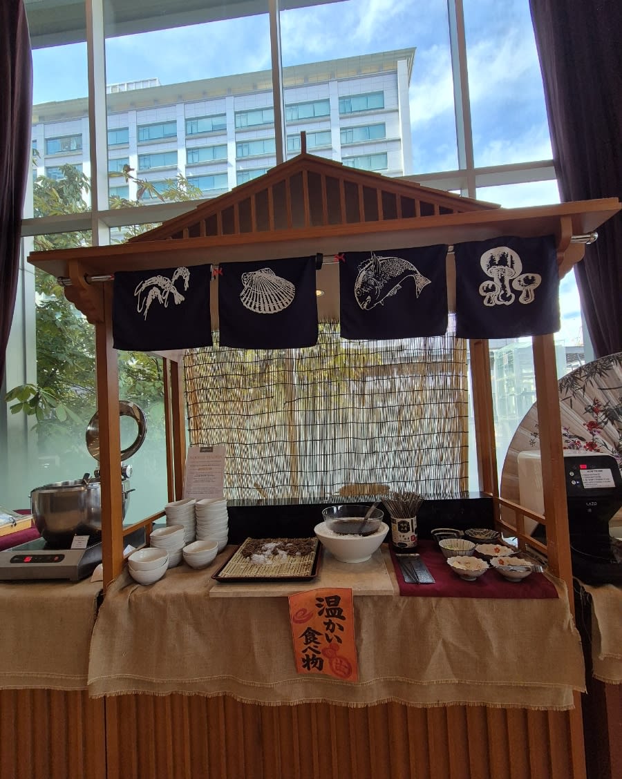 Buffet stall styled as a small Japanese food stand with noren curtains, next to the windows