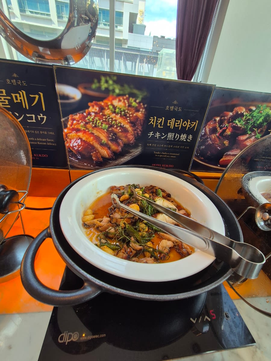 Hot buffet station with a white bowl of chicken teriyaki and serving tongs