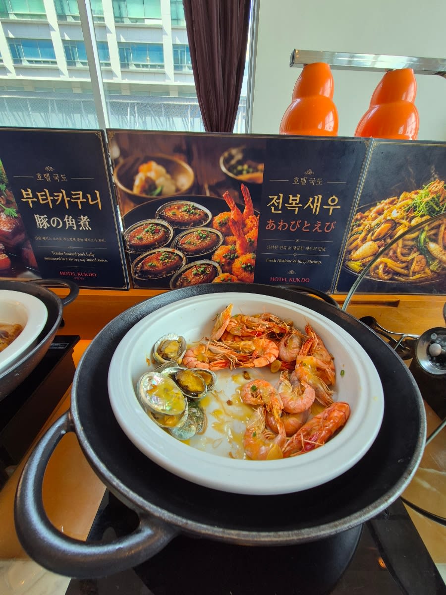 Hot buffet station with a white bowl of prawns and shellfish