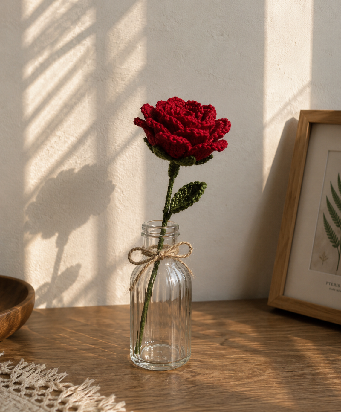 Realistic red crochet rose stem in a glass bottle vase for home decor and romantic gift ideas.