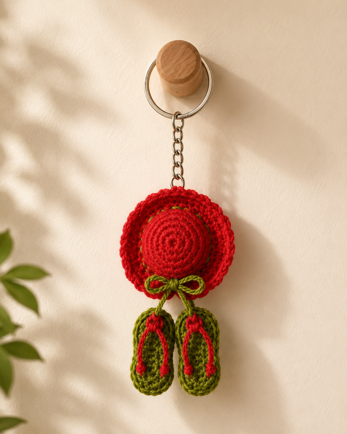 Scarlet Garden Hat & Sandals Keychain hanging on a wooden wall hook, bright red hat charm with green bow and matching green sandals.