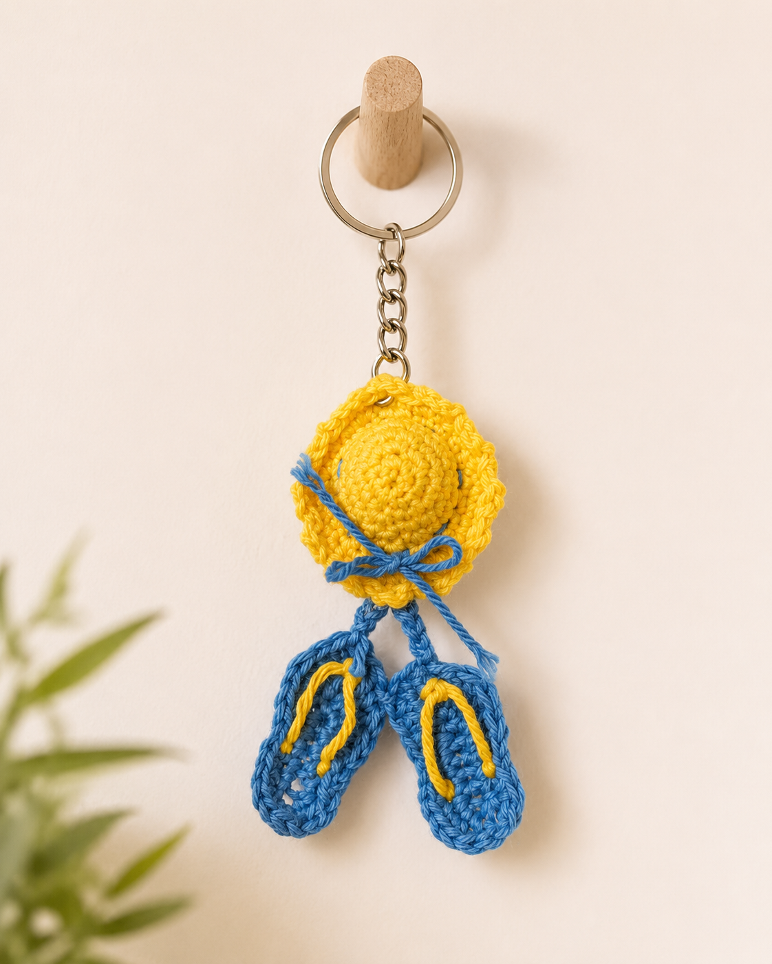 Sunny Seaside Hat & Sandals Keychain hanging on a wooden wall hook, bright yellow hat charm with blue bow and matching blue sandals.