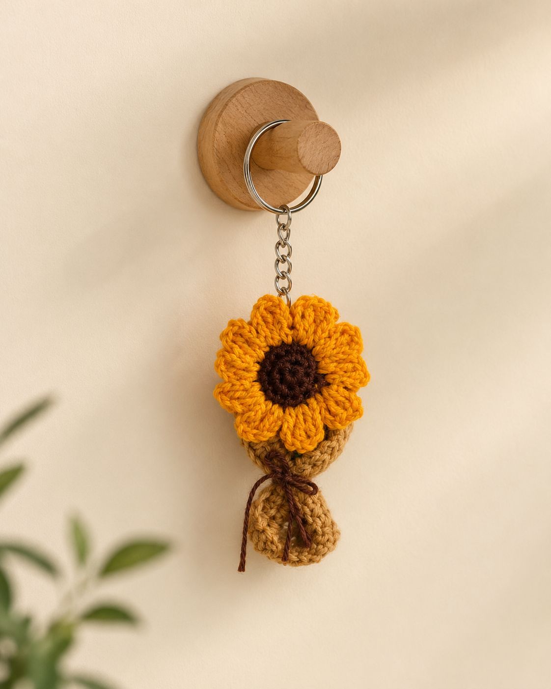 Sunflower Bouquet Keychain hanging on a wooden wall hook, handmade yellow crochet flower charm with brown wrap and metal keyring.