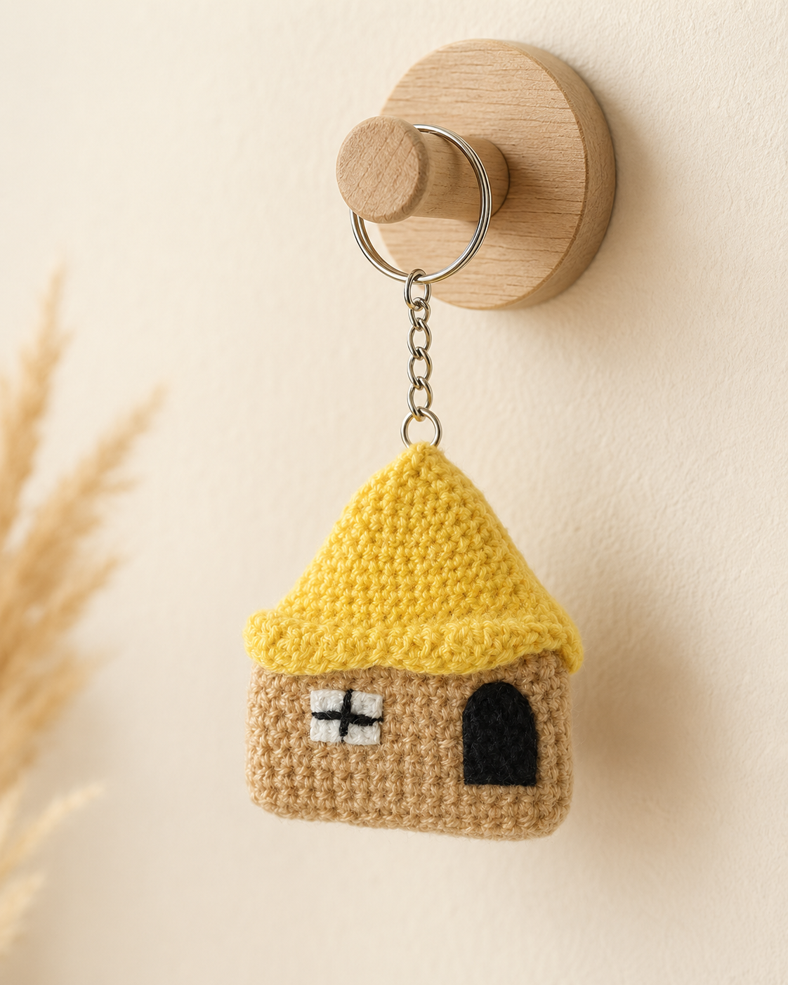 Crochet House Keychain placed with keys on a wooden table, handmade yellow roof house charm for keys and bags.