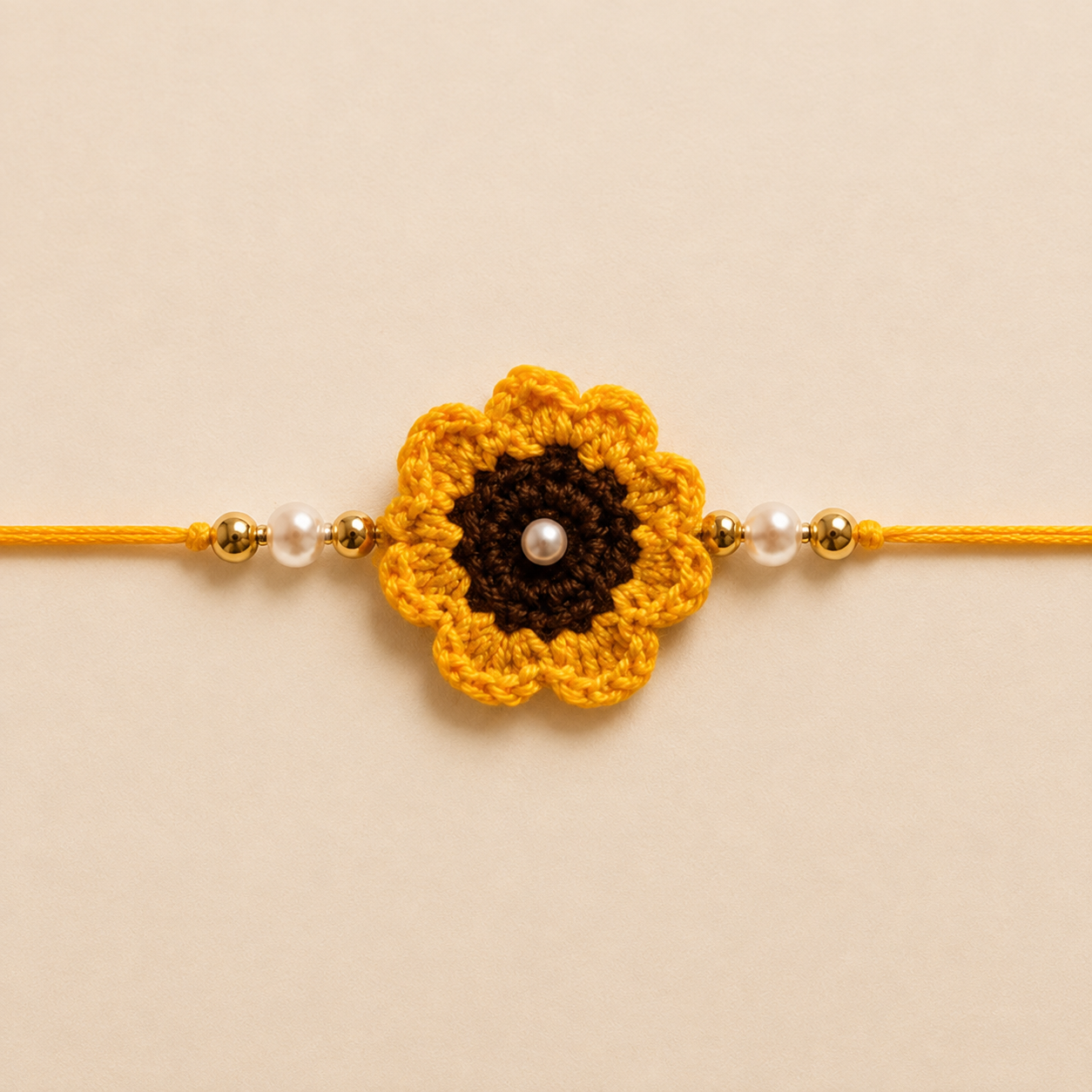 Close-up of yellow sunflower rakhi with brown center, pearl bead detail, white pearl-style beads, gold-tone side beads, and yellow tying thread.