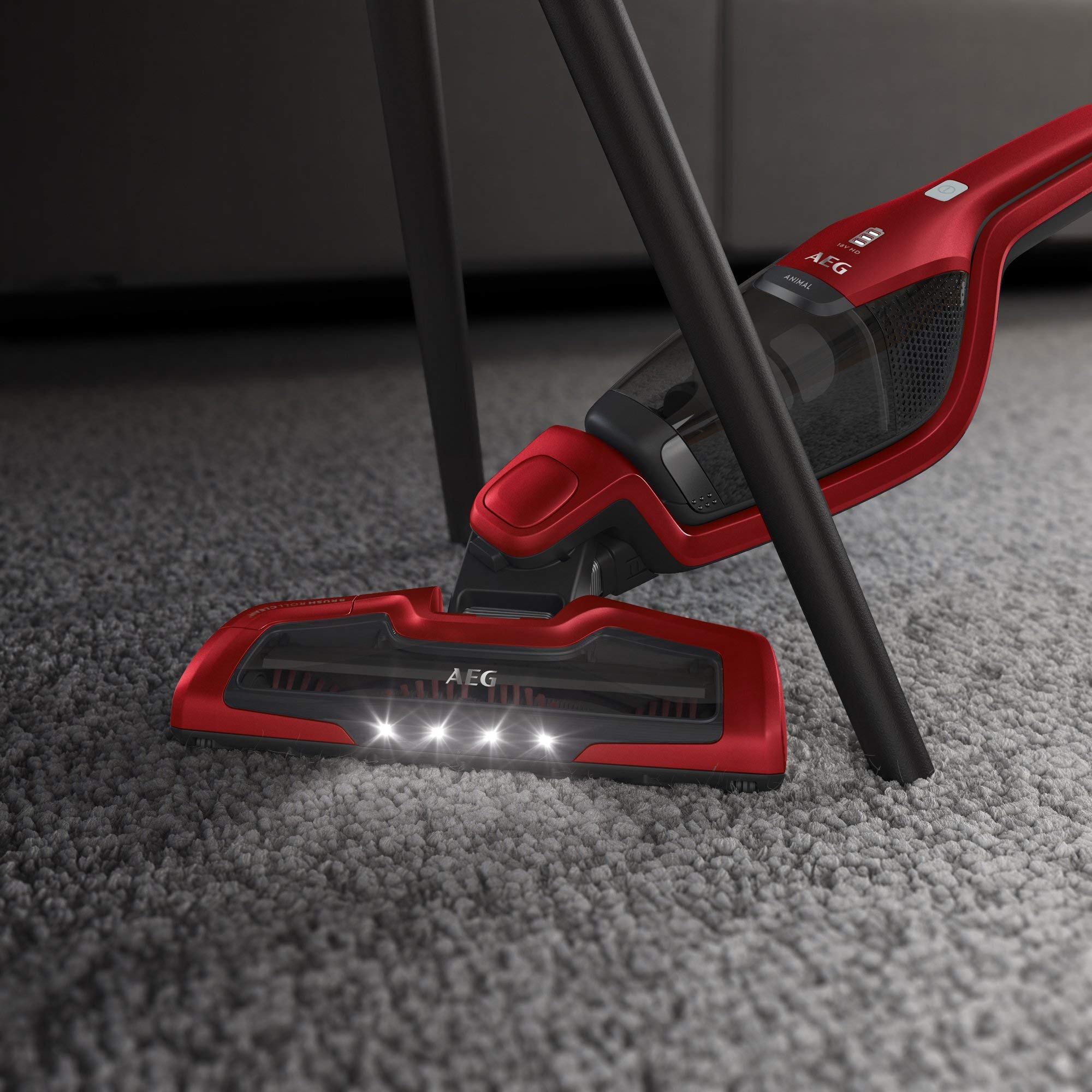 Aspiradora AEG roja con LED limpiando alfombra bajo mueble