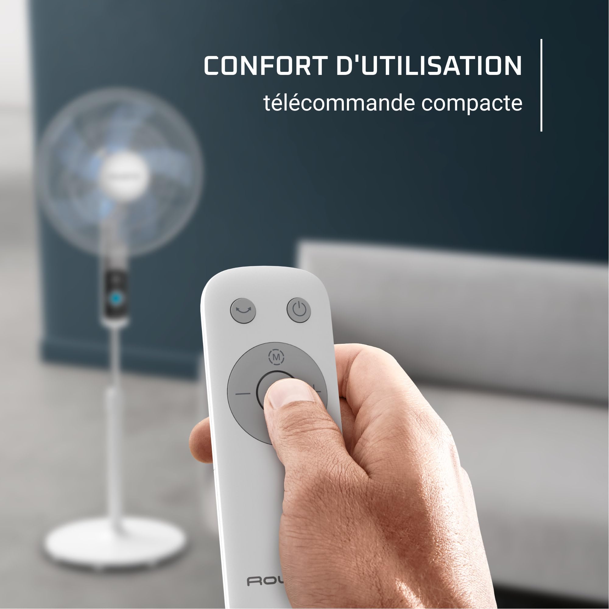 Mano sujetando el mando a distancia compacto del ventilador de pie Rowenta Turbo Silence VU5650 en un salón