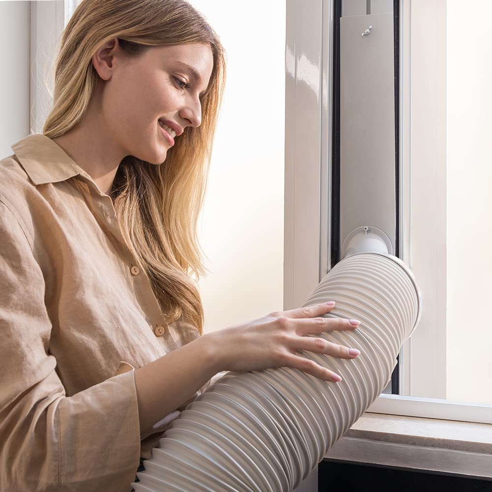 Mujer joven instalando el tubo de extracción del aire acondicionado portátil Cecotec en una ventana