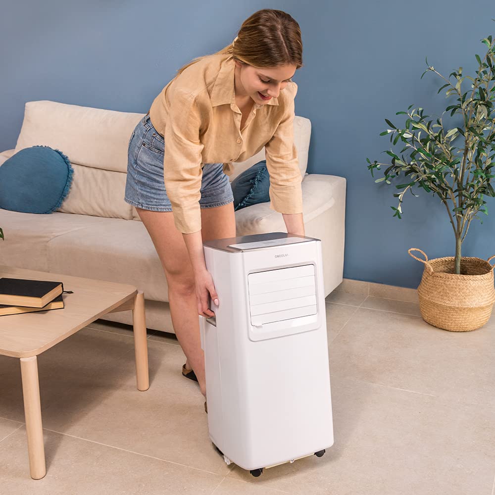 Mujer moviendo un aire acondicionado portátil blanco Cecotec ForceClima 7100 con ruedas en un salón moderno