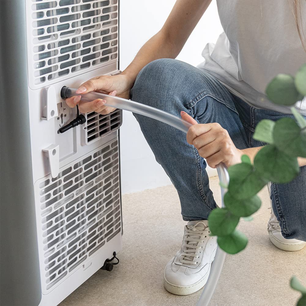 Persona conectando el tubo de drenaje a la parte trasera de un aire acondicionado portátil Cecotec ForceClima 9100.