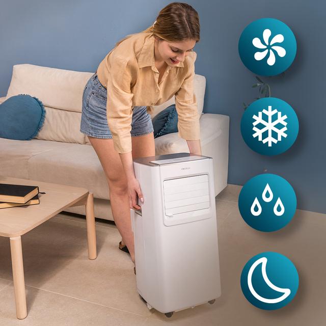 Mujer junto a un aire acondicionado portátil blanco en salón moderno con iconos de funciones de frío, ventilación y modo noche