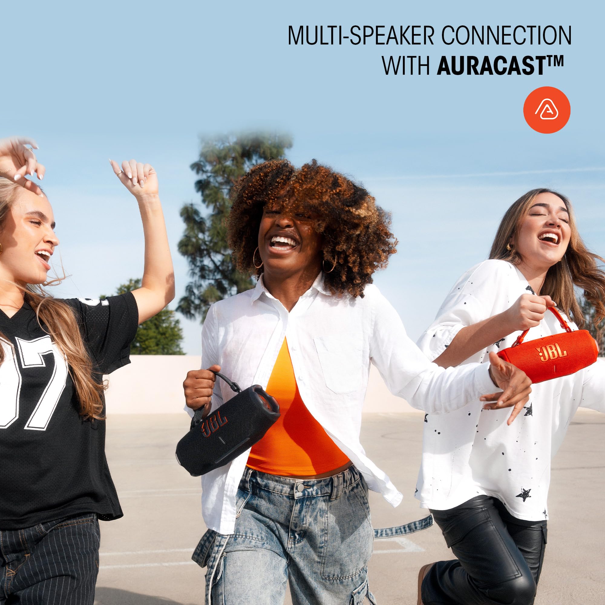 Tres jóvenes disfrutando música con altavoces JBL Charge 6 en exteriores, destacando la conexión multi-altavoz Auracast.