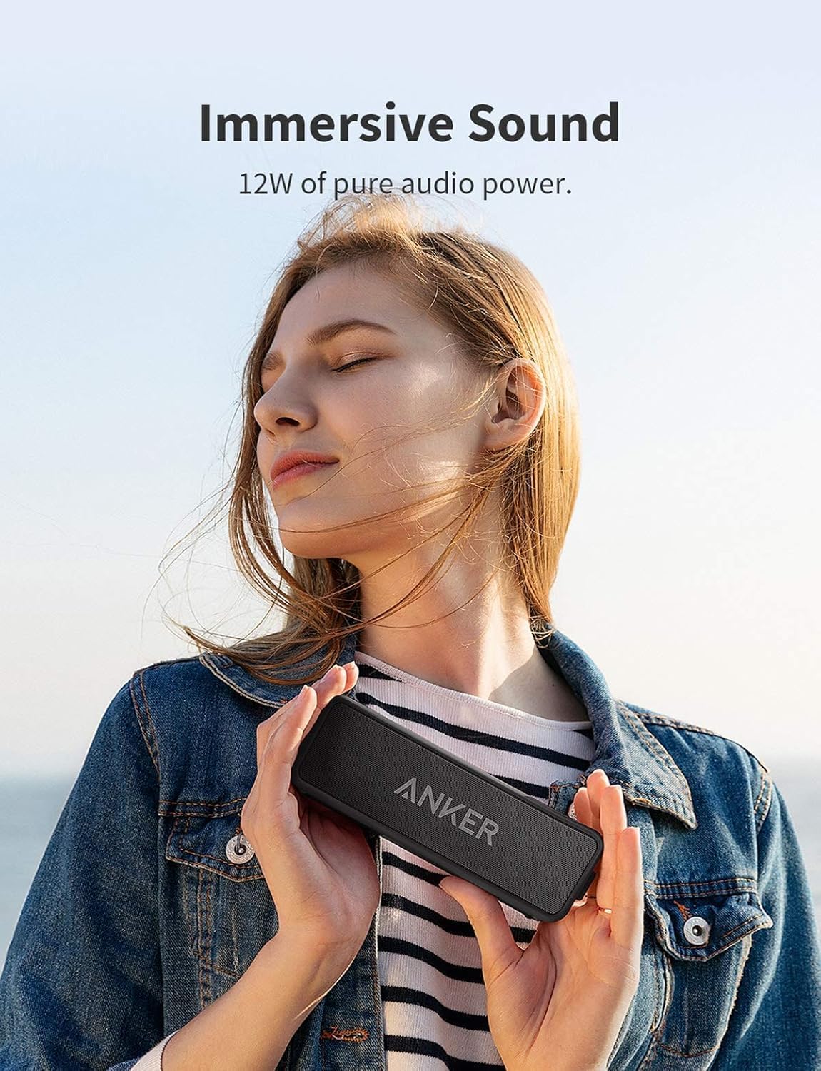 Mujer joven sosteniendo altavoz Bluetooth Anker Soundcore 2 negro con sonido estéreo de 12W