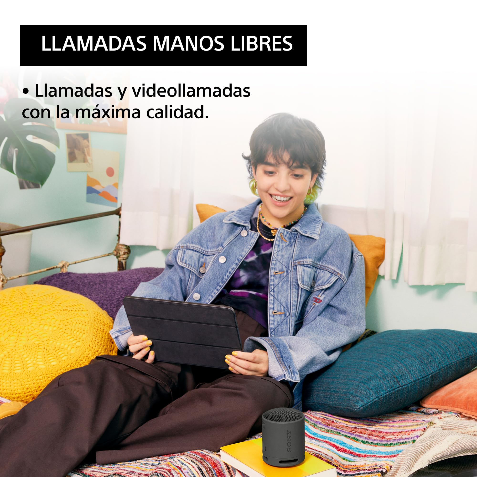 Mujer joven usando tablet con altavoz Sony SRS-XB100 negro para videollamadas manos libres.