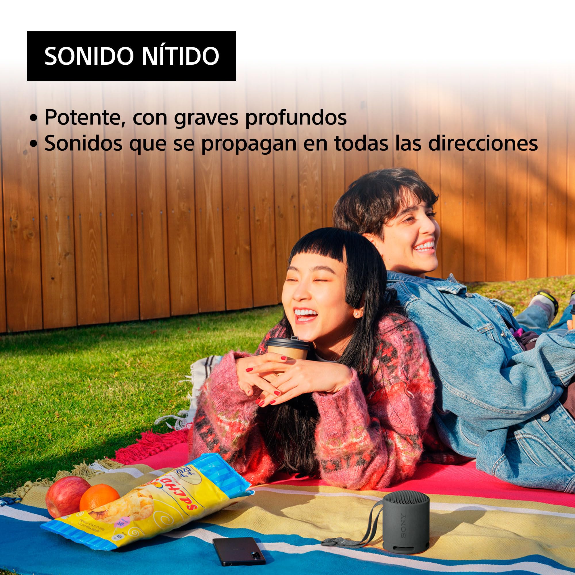 Sony SRS-XB100 altavoz Bluetooth negro con jóvenes disfrutando música al aire libre en picnic.