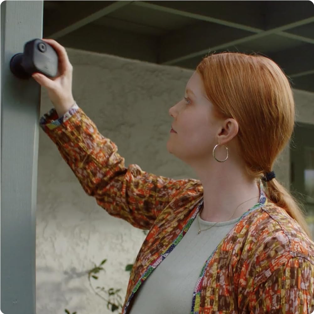 Mujer instalando cámara Blink Outdoor 4 en poste gris exterior