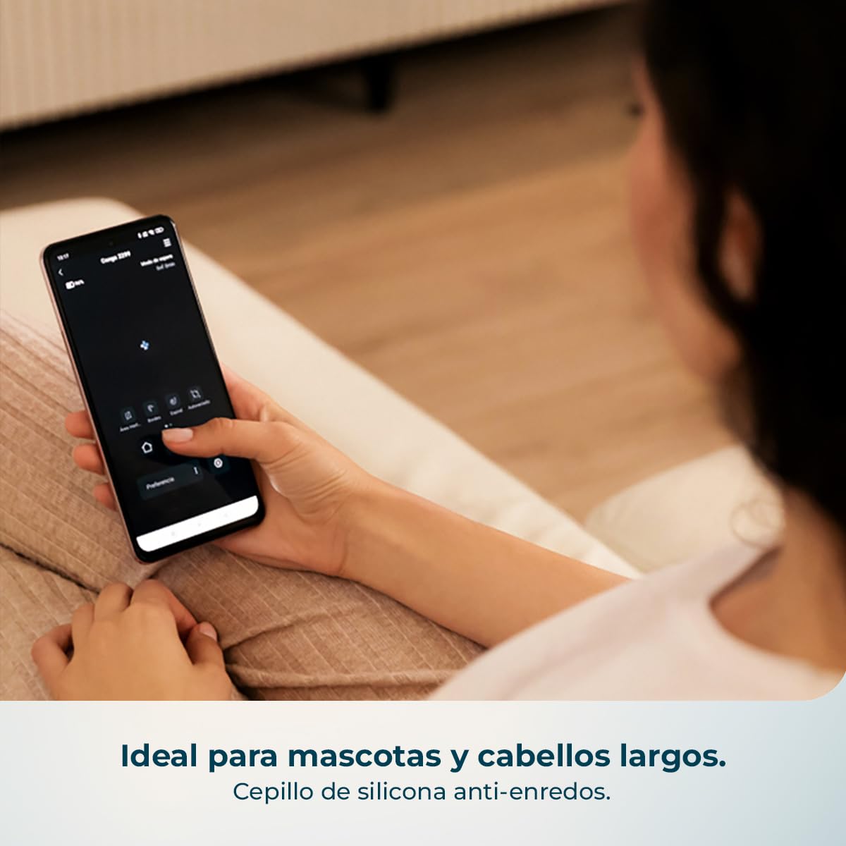 Persona usando app móvil del robot aspirador Cecotec en sofá