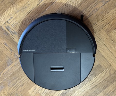 Vista superior de un robot aspirador iRobot Roomba negro sobre suelo de parquet