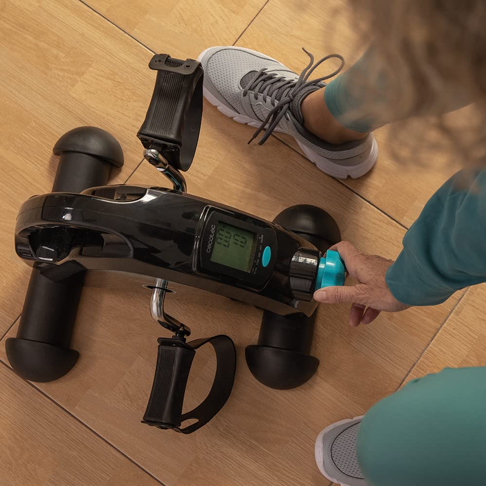 Pedalier estático Cecotec DrumFit Cycle Compact negro con pantalla LCD y ajuste manual de resistencia sobre suelo de madera.