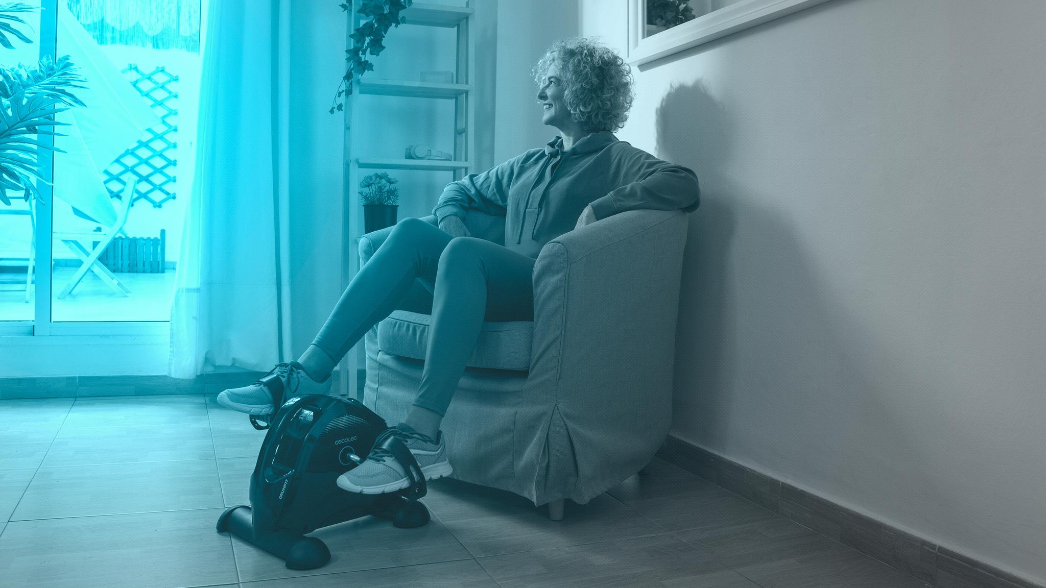 Mujer ejercitándose con mini pedalina estática Cecotec en el salón de casa
