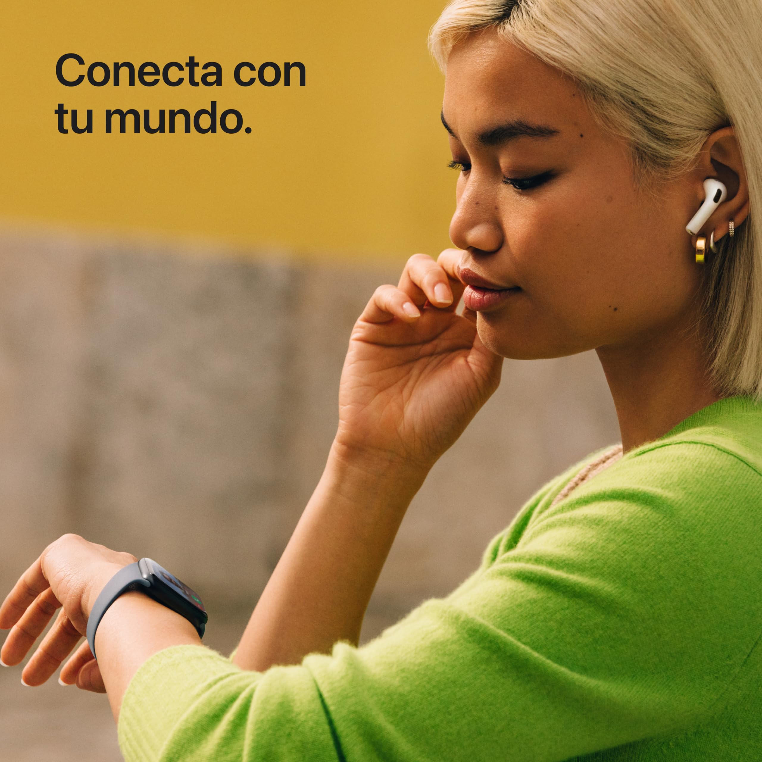 Mujer con AirPods revisa su Apple Watch SE 3 color medianoche mientras luce un suéter verde.