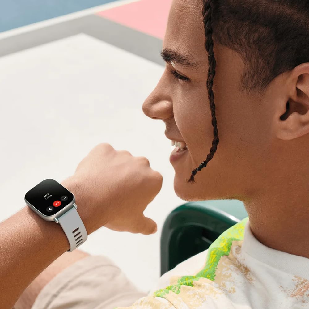 Hombre joven sonriente usando Xiaomi Redmi Watch 5 Active con pantalla de llamada Bluetooth activa en su muñeca.
