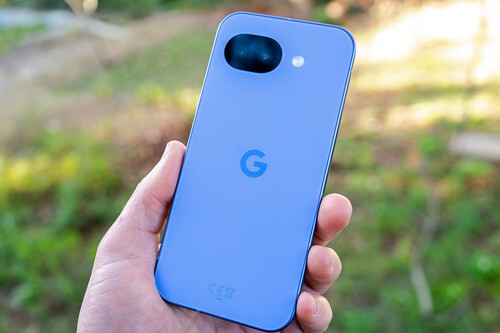 Smartphone Google Pixel azul claro visto desde atrás, sostenido en una mano con fondo natural borroso.