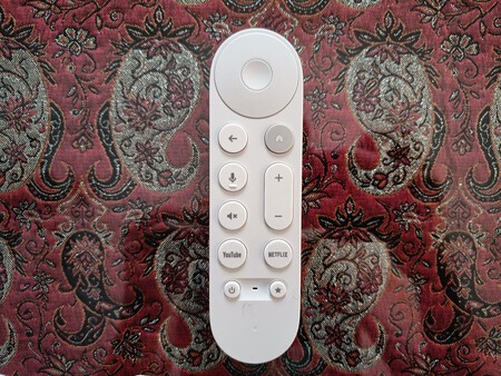 Mando a distancia blanco con botones funcionales sobre fondo decorativo