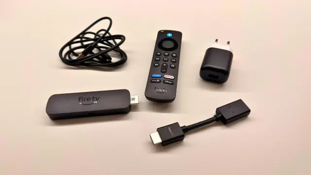 Dispositivo Fire TV con mando y accesorios sobre fondo claro