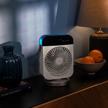 Ventilador portátil blanco sobre mesa con lámpara y frutas